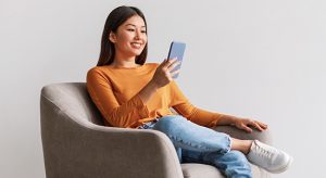 Smiling female sitting on a chair smiling and looking at mobile phone.