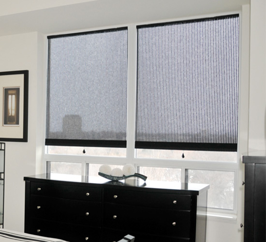 Black shades on two windows in a modern white bedroom.